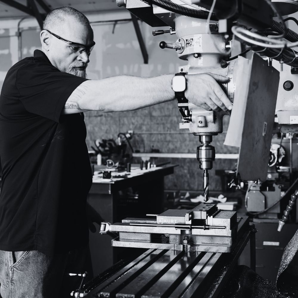 Technician machining a metal component in an industrial fabrication shop