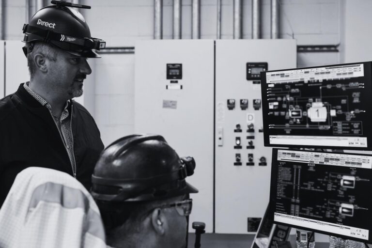 Technicians reviewing industrial control system data on SCADA and process monitoring screens.
