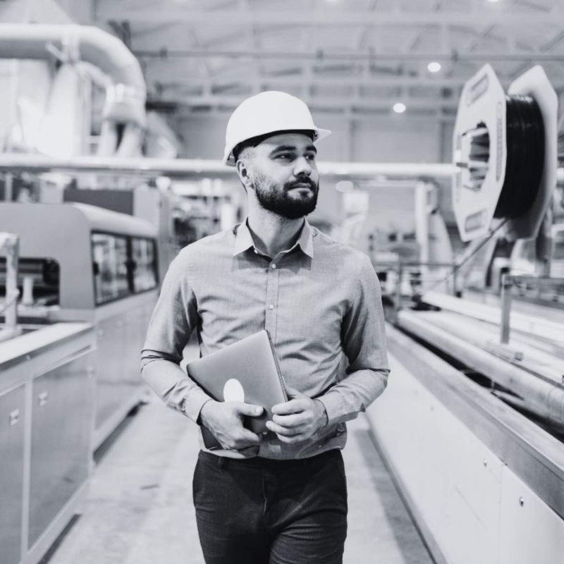 Manufacturing engineer walking through an industrial facility with production equipment