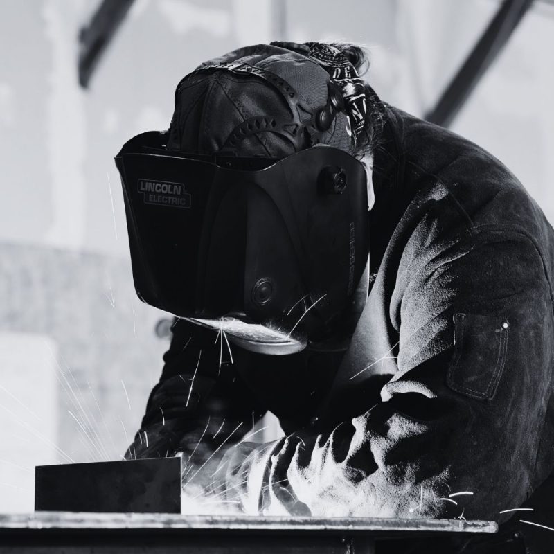 Welder fabricating a custom metal component in an industrial shop